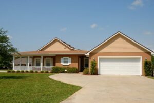 An image of a house with a white garage door and a long driveway
