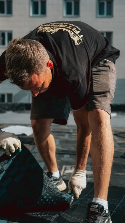 worker handling asphalt shingles